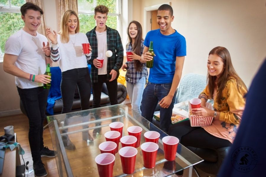 people standing around a beer pong table