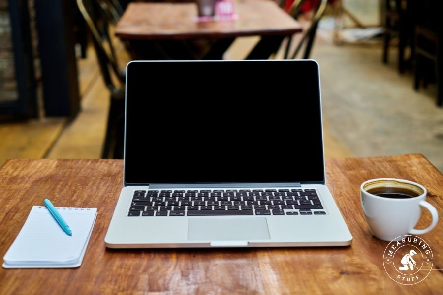 Laptop on a table with coffee and notepad