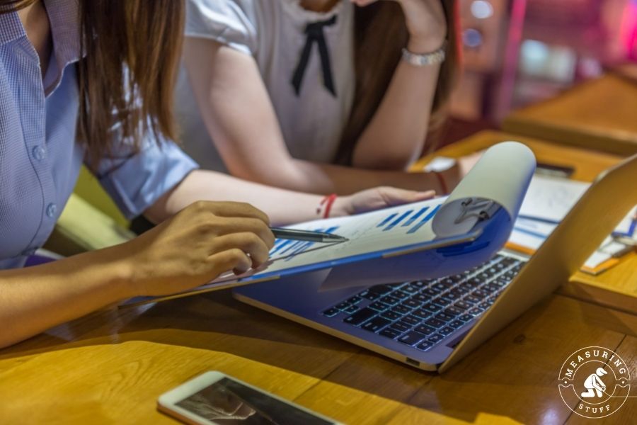 person using a pen to scan over a clipboard paper