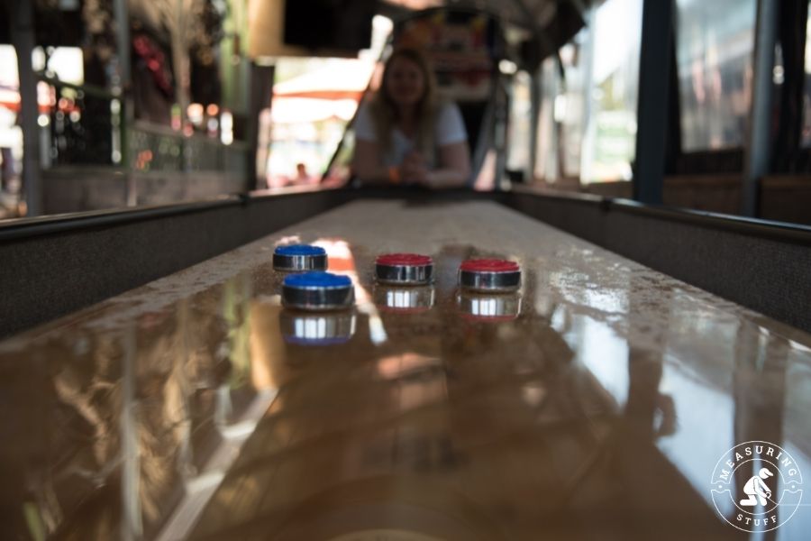 shiny shuffleboard table with red and blue pucks