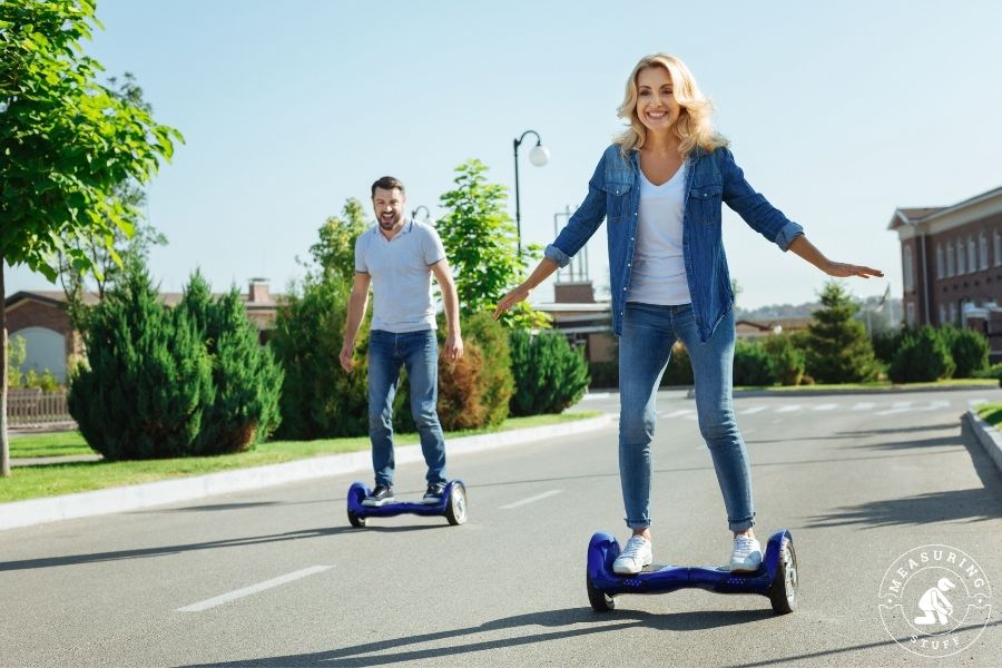 man and woman riding blue hoverboards on street