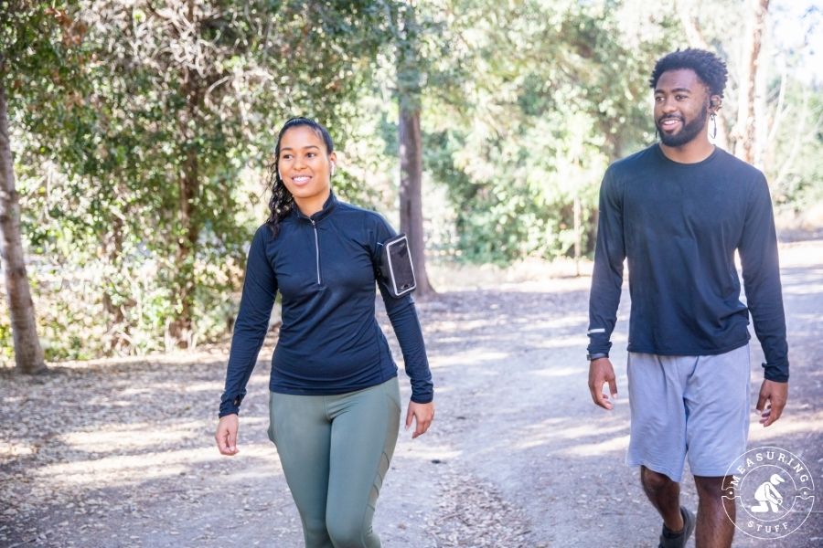athletic man and woman walking on trail