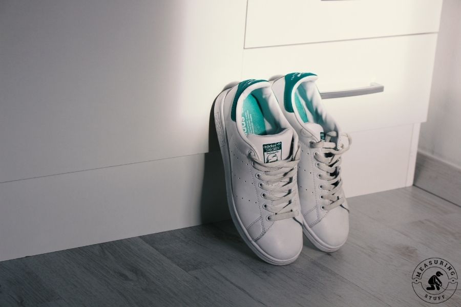 pair of white sneakers leaning against wall