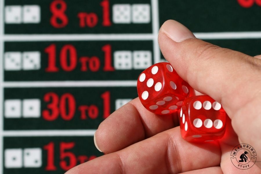 person holding red dice with odds chart