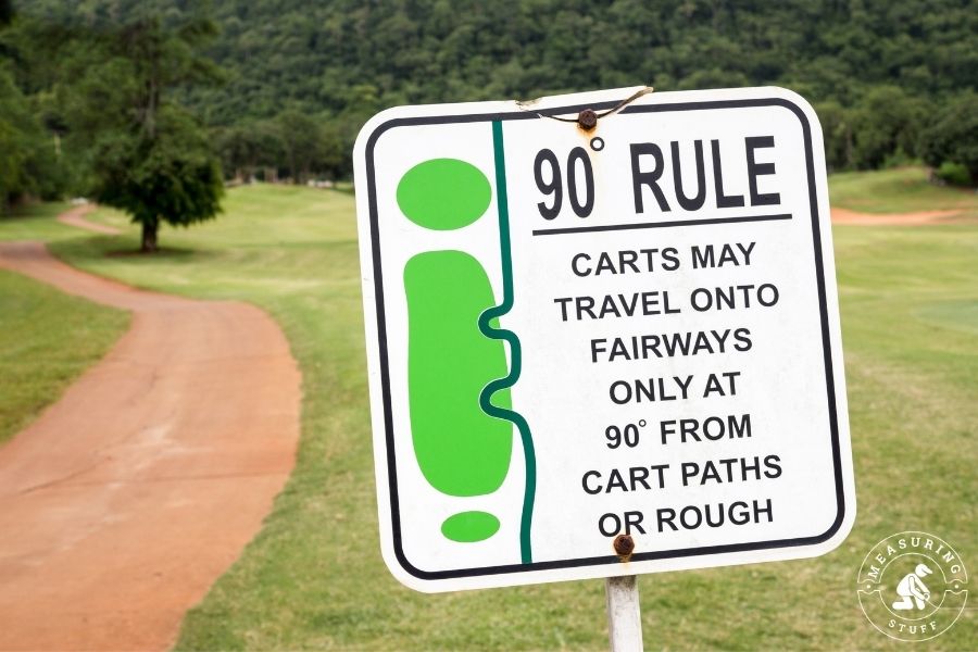 white sign on golf course with rule for carts