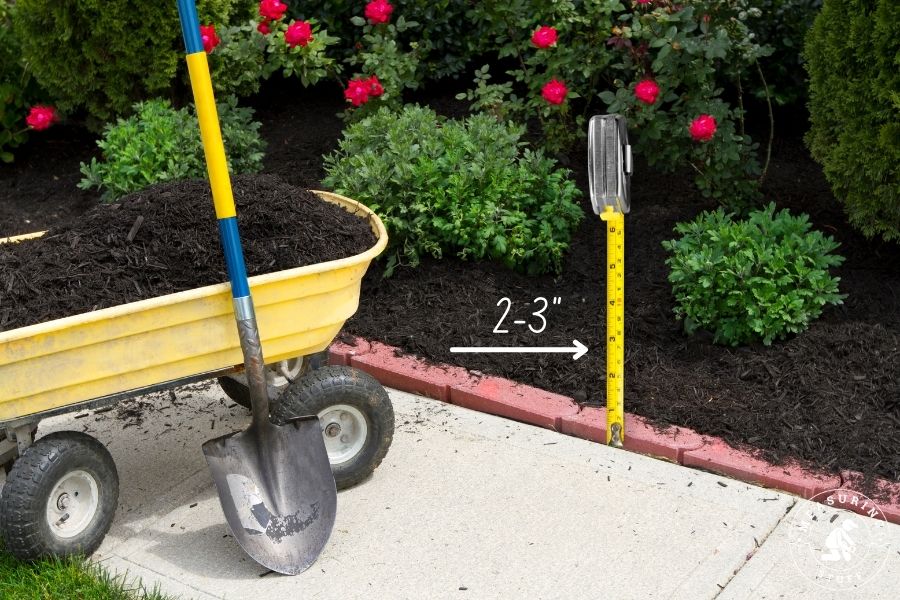 whellbarrow and shovel next to a garden bed of mulch