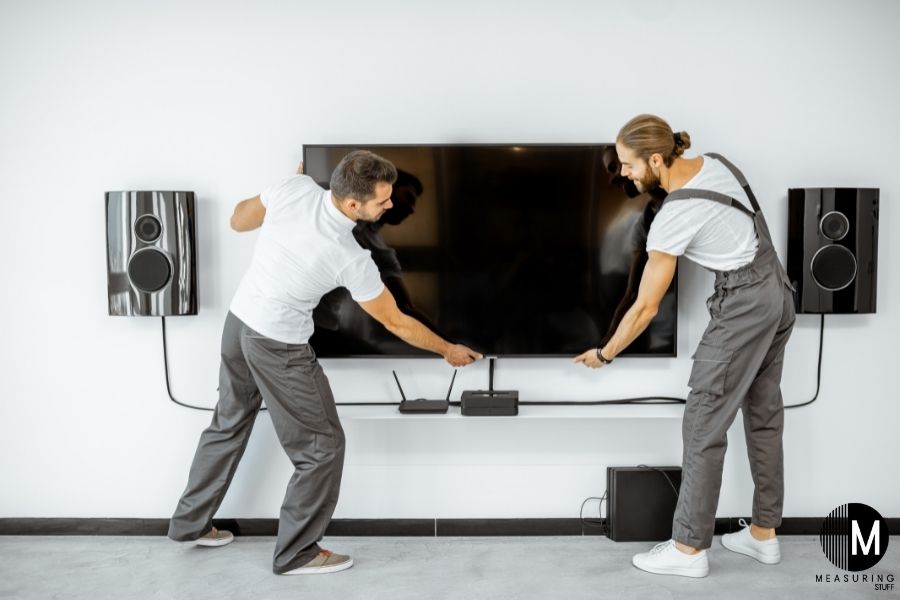 2 men wall mounting a tv