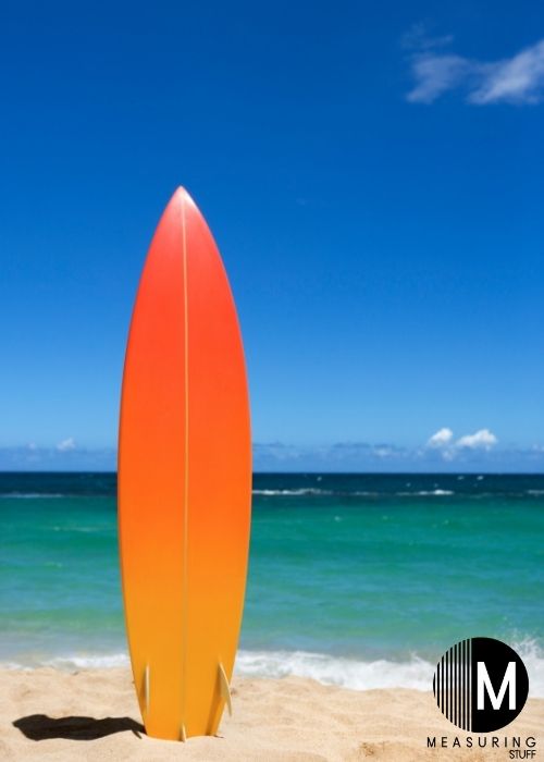 orange surfboard on sand