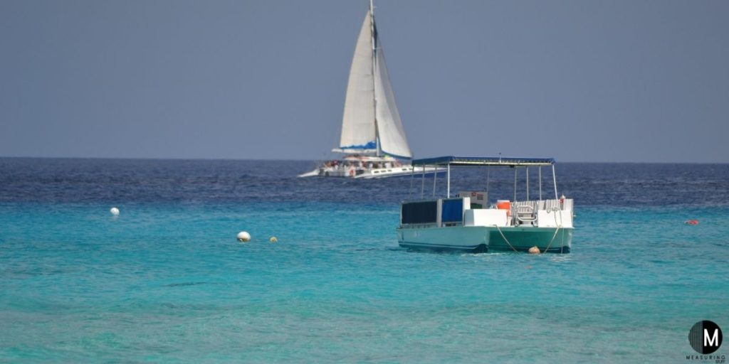 pontoon boat on water next to sailboat