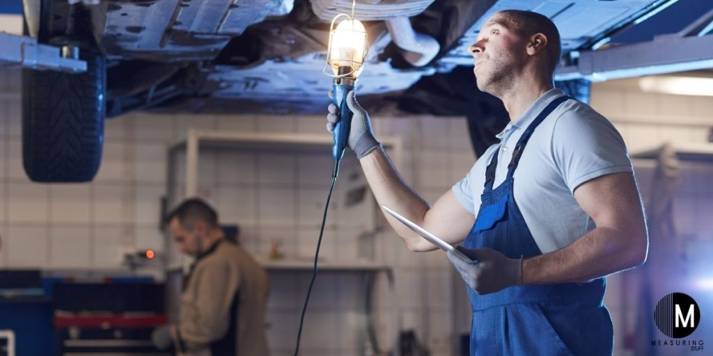 mechanic holding light under car