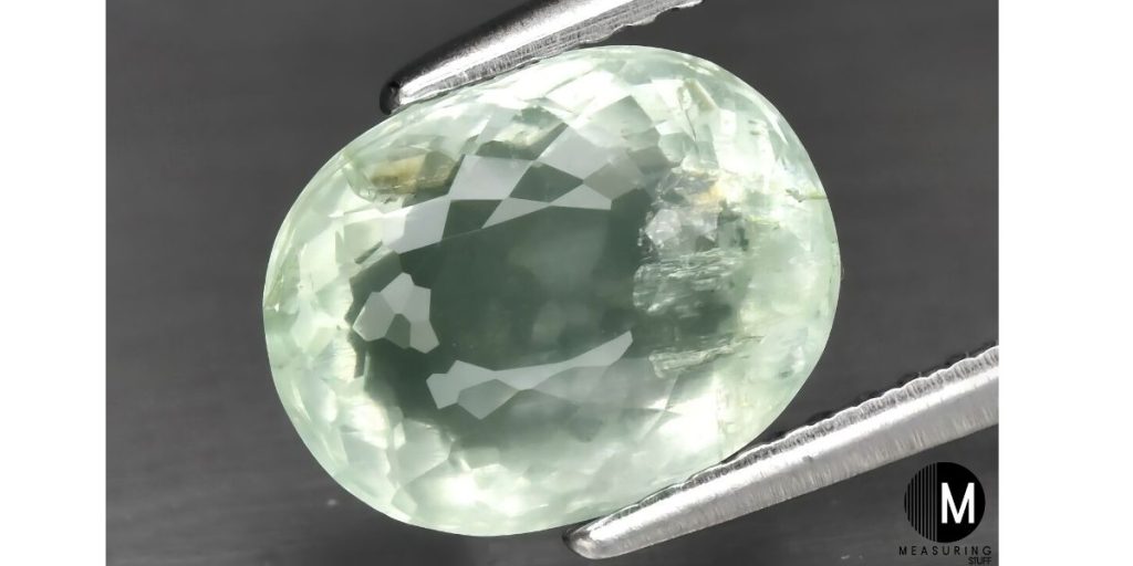 green beryl gemstone held by tweezers