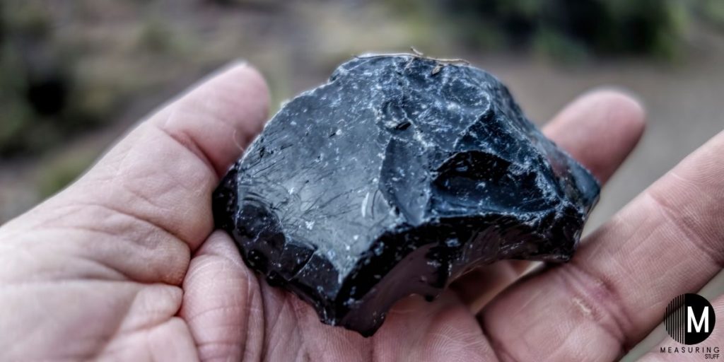 holding a piece of obsidian rock