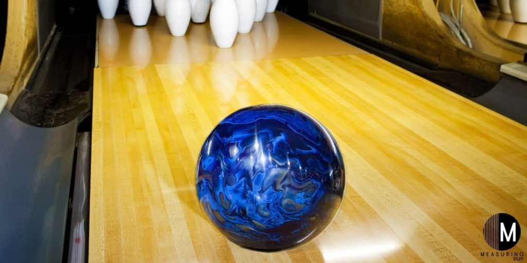 blue bowling ball on wooden bowling lane
