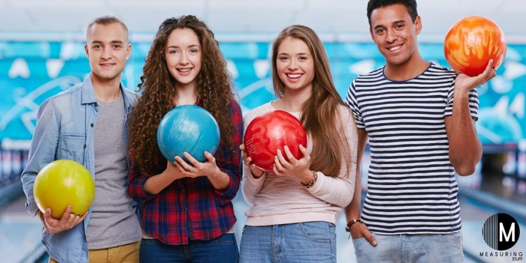 men and women holding bowling balls