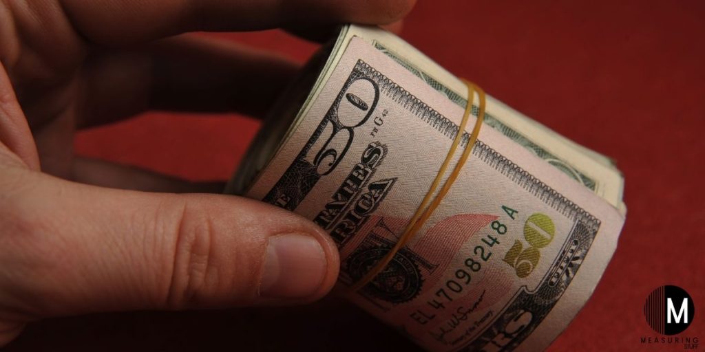 holding a roll of $50 bills