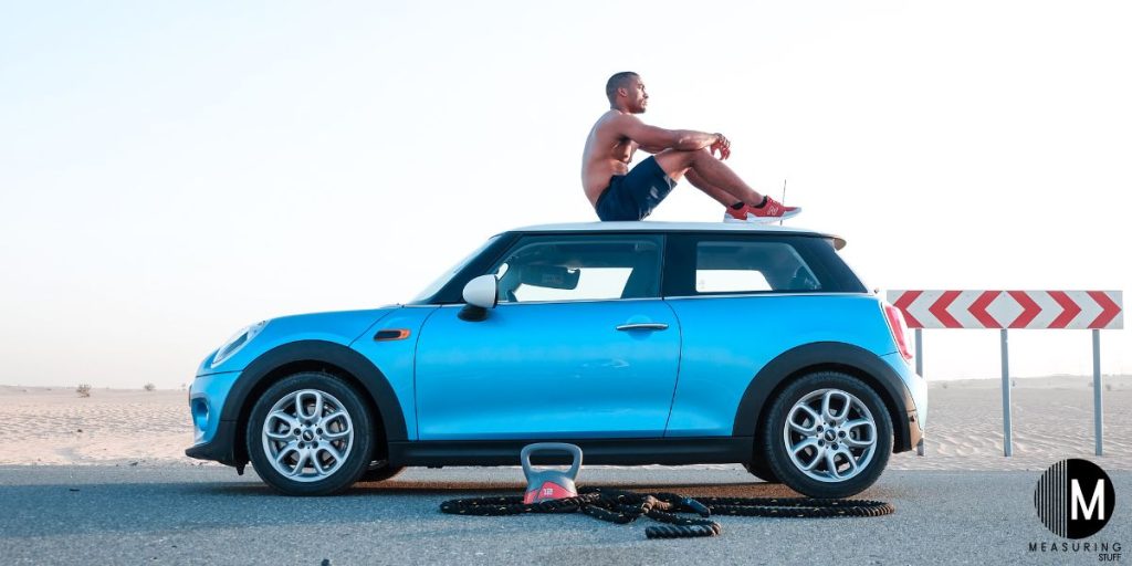 man sitting on top of a mini cooper