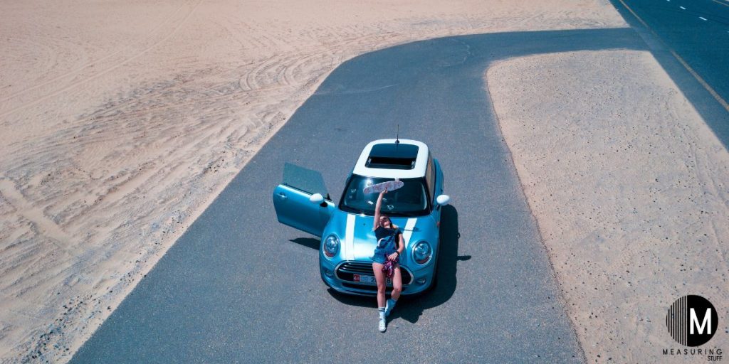 woman holding a skateboard on a mini cooper