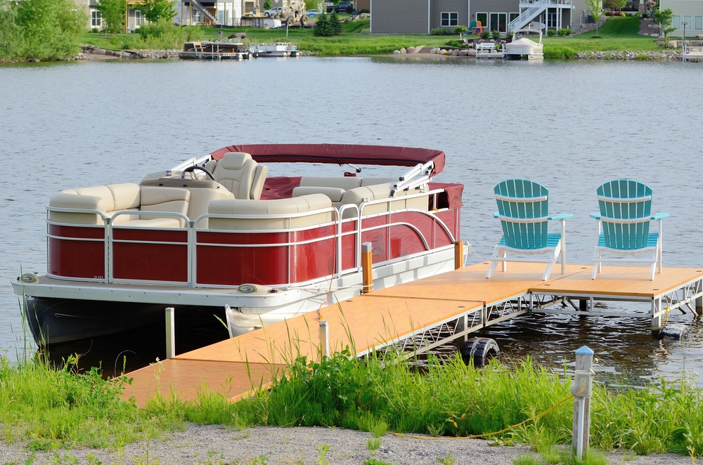 Red Pontoon Boat Tied to a Dock With Two Chairs