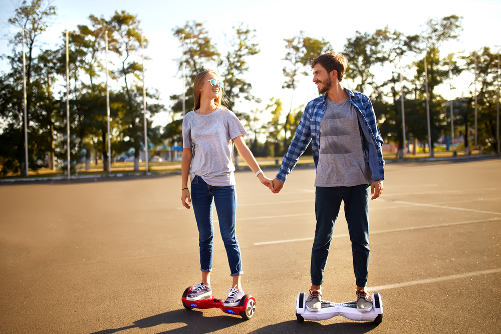 man and woman riding hoverboards in the park