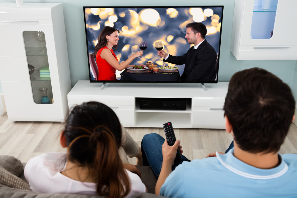 Young Couple Watching Romantic Movie On Television Together At Home