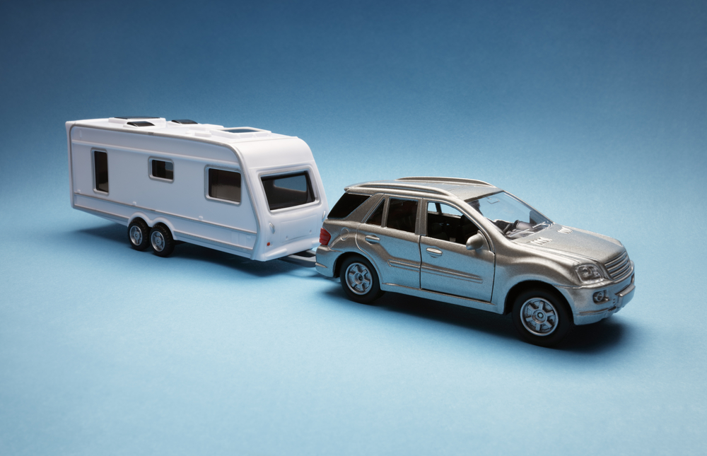 Toy car towing a caravan of generic design on blue background