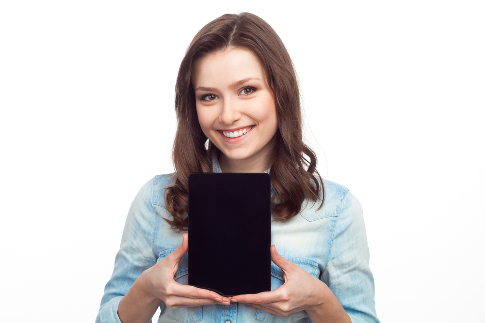 Smiling young woman showing the screen of her device isolated on white.