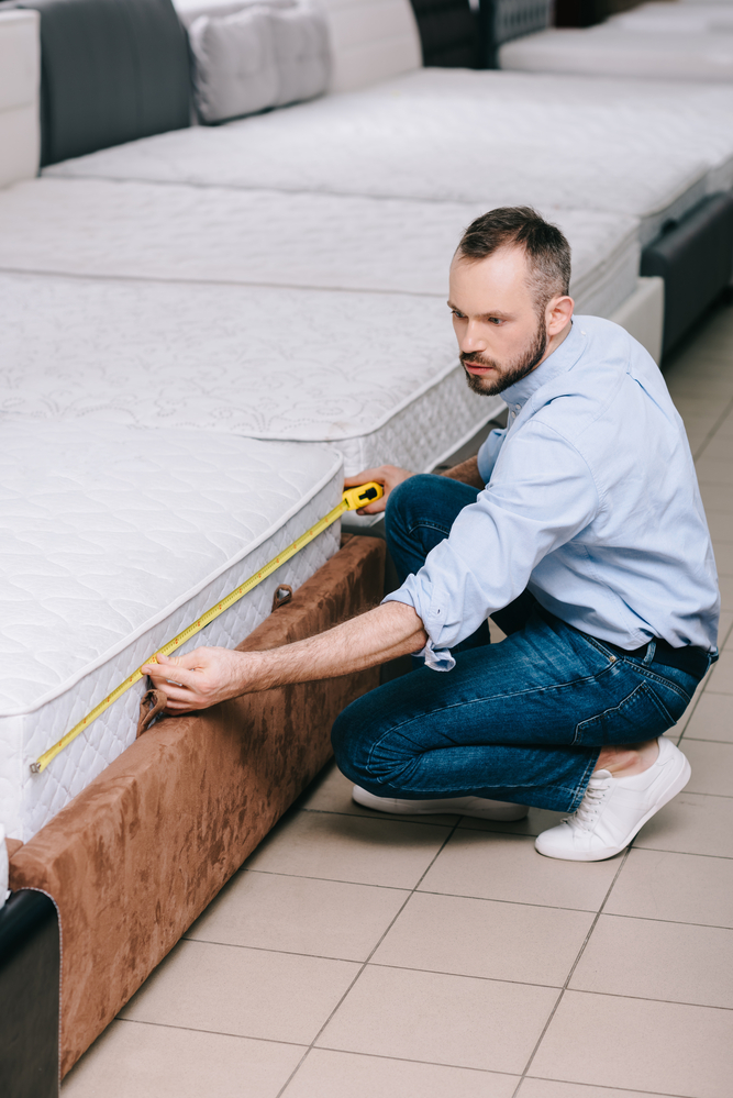 man measuring a bed mattress