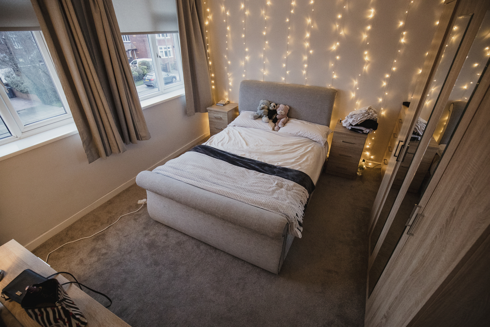 Empy student bedroom decorated with twinkle lights and teddy bears.