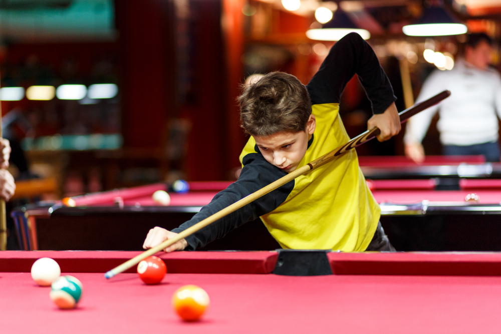 young boy playing pool
