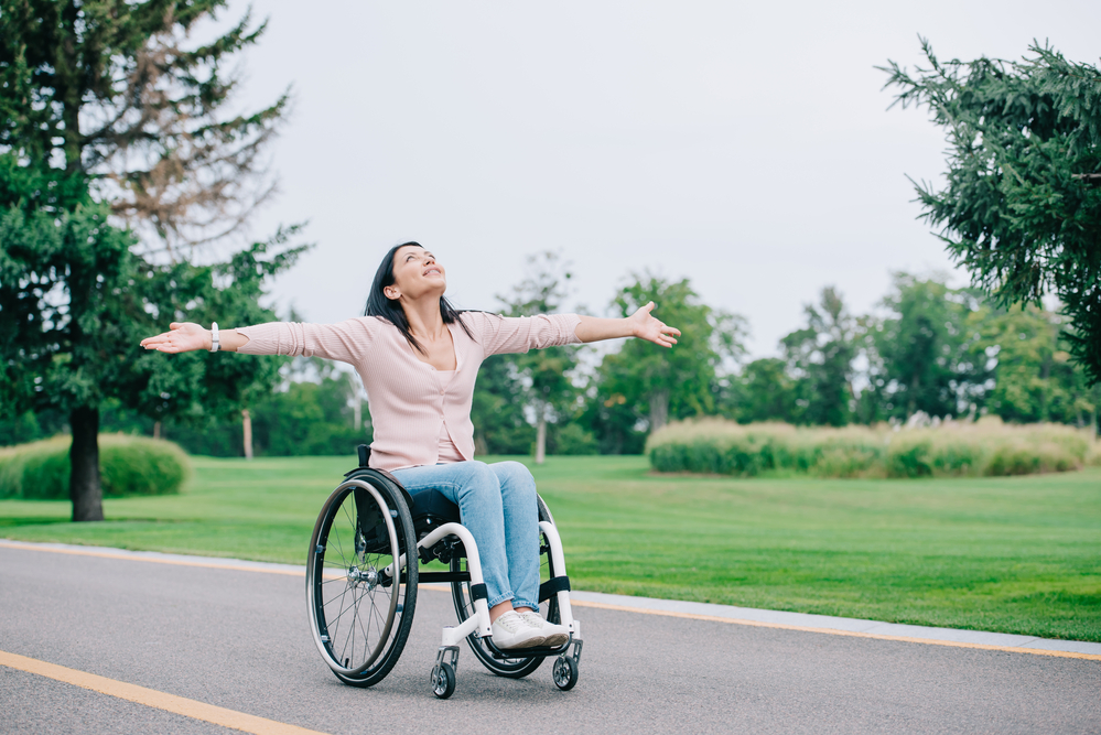 woman in a lightweight wheelchair on a road with arms extended