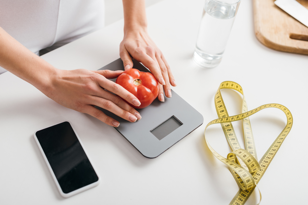 woman placing a tomato on a digital scale