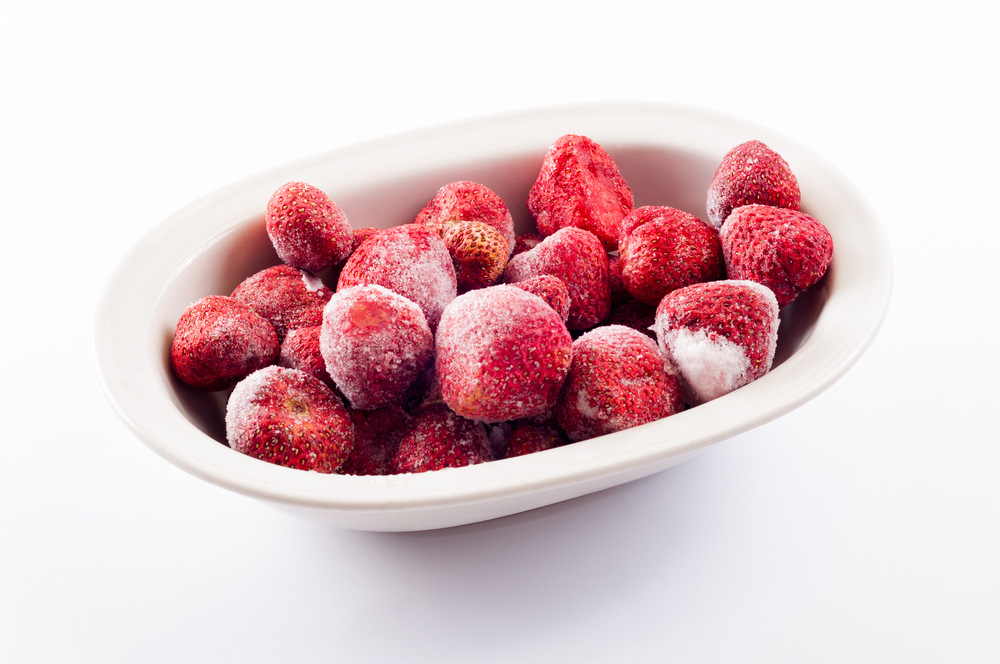 Couple of frozen strawberries laying in the white porcelain bowl.