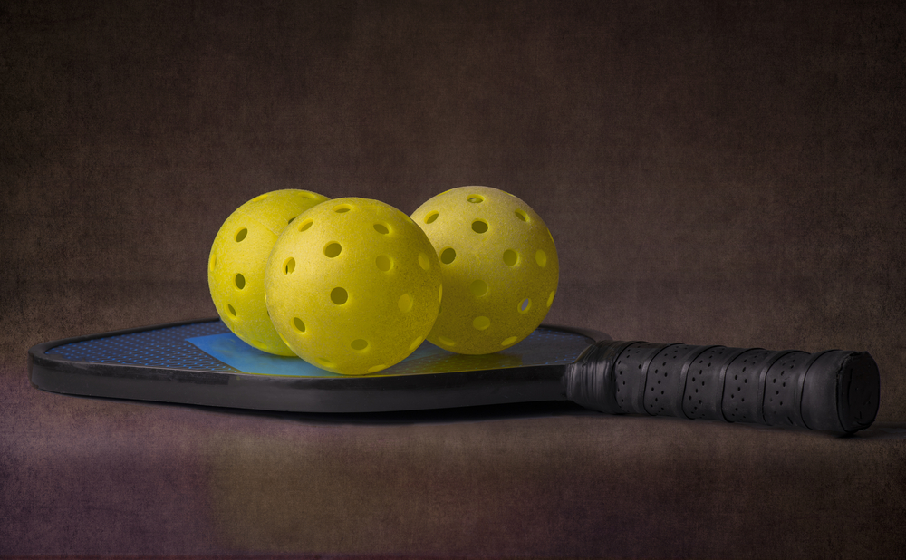 pickleball paddle with yellow whifleballs