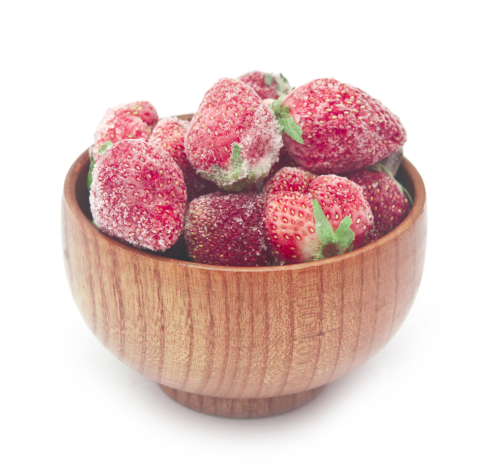 Frozen strawberries in a wooden bowl on white background