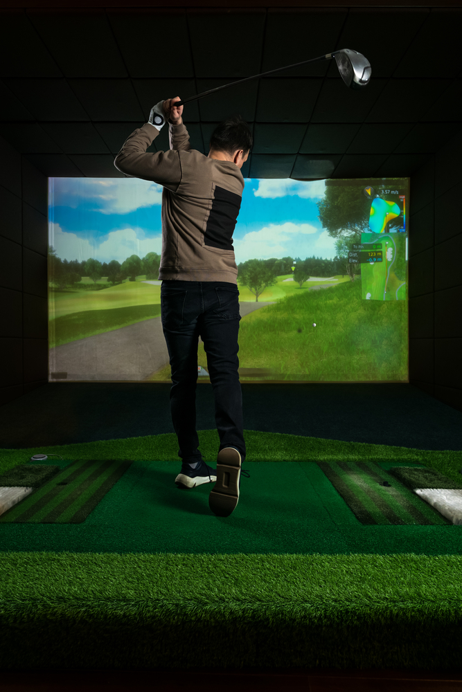man swinging a club using golf simulator