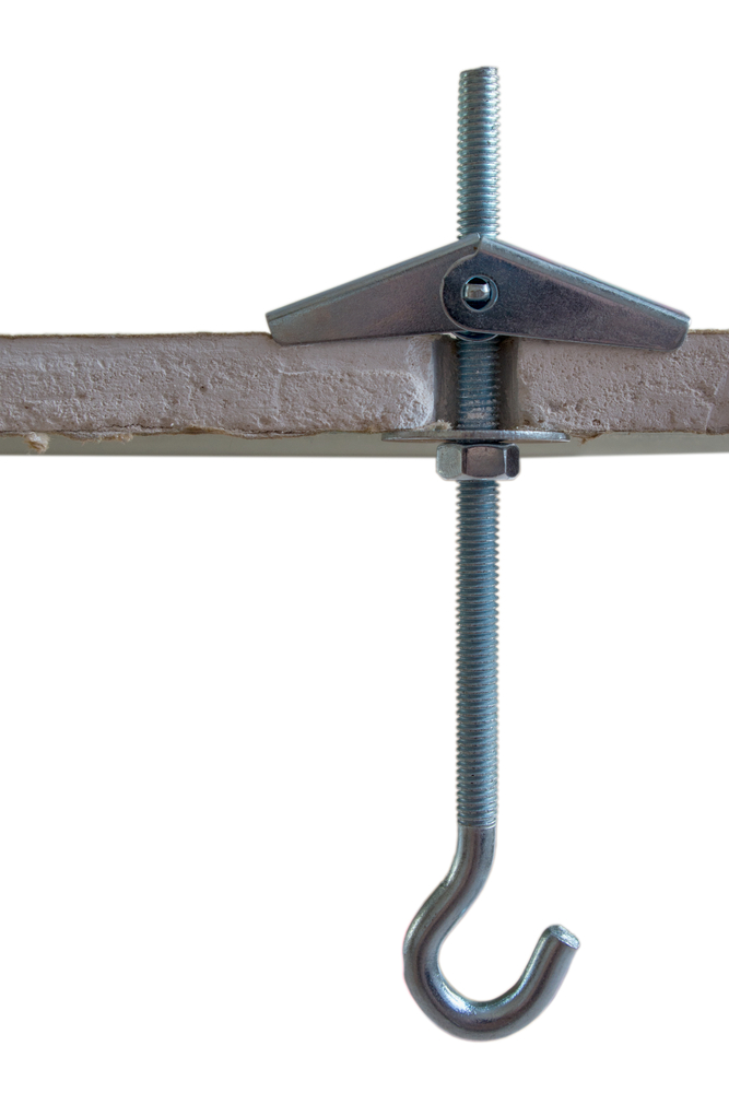 Metal folding spring anchor with hook mounted and screwed into a pre-drilled hole in a sheet of moisture-proof drywall, a view of a section of drywall, isolated on a white background.