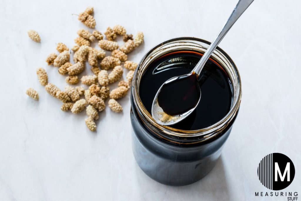 glass jar with spoon filled with molasses