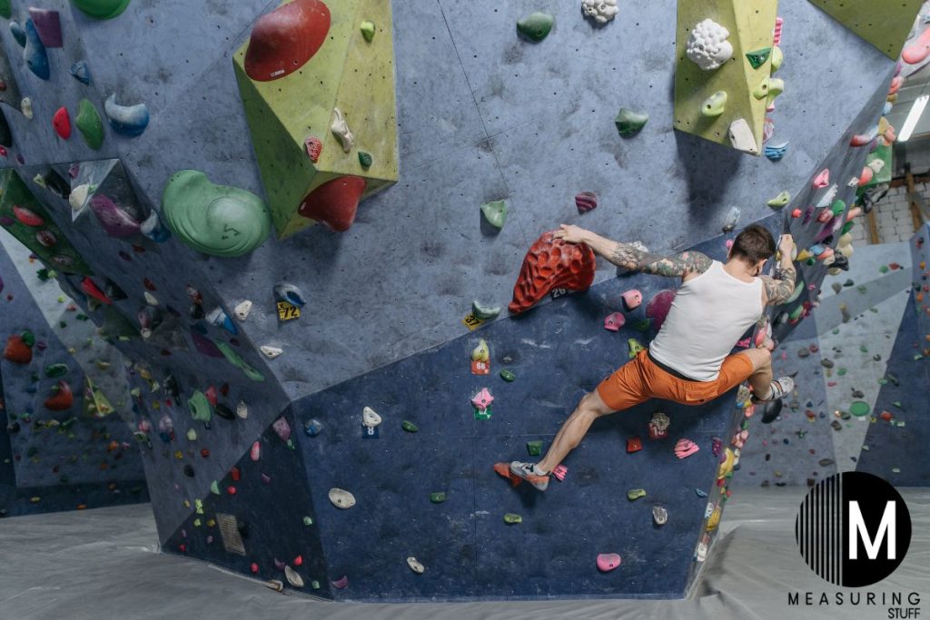 man climbing a wall with multi colored rocks