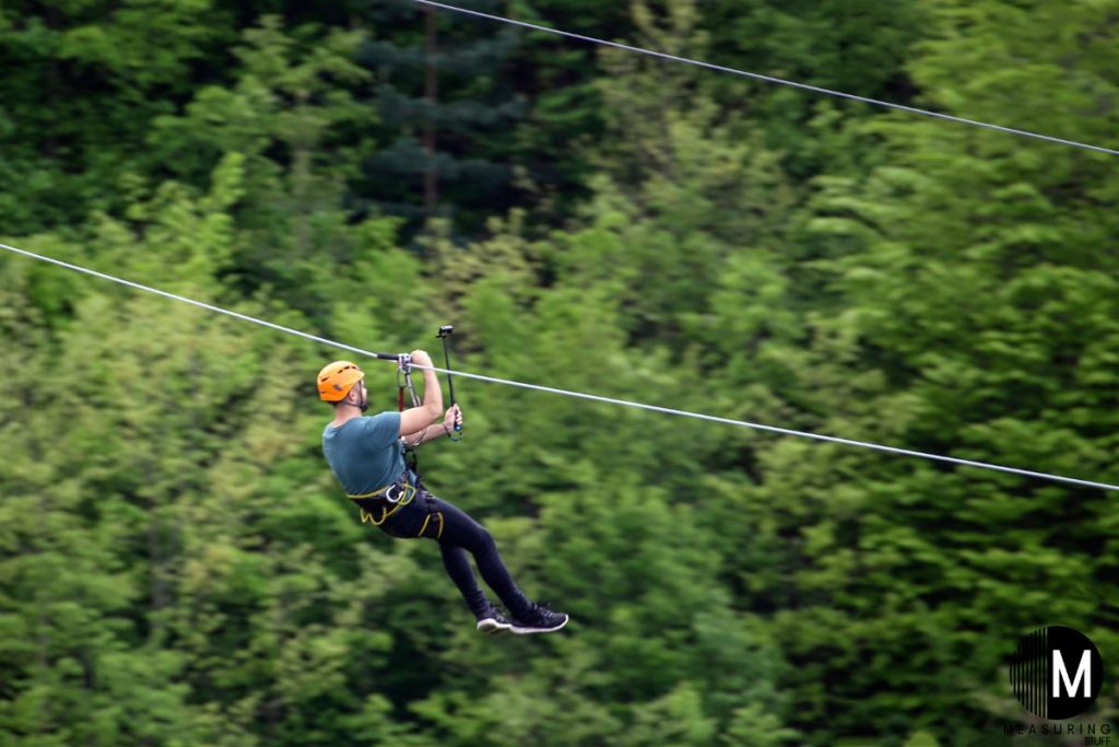man zip lining with trees beside