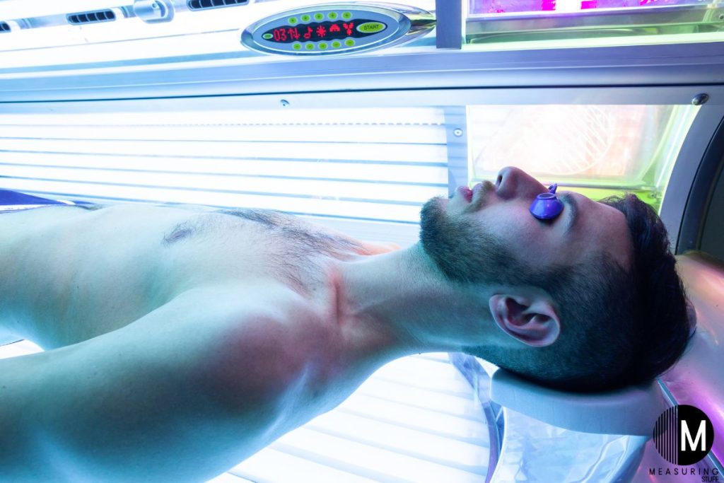 man laying on back wearing goggles in a tanning bed