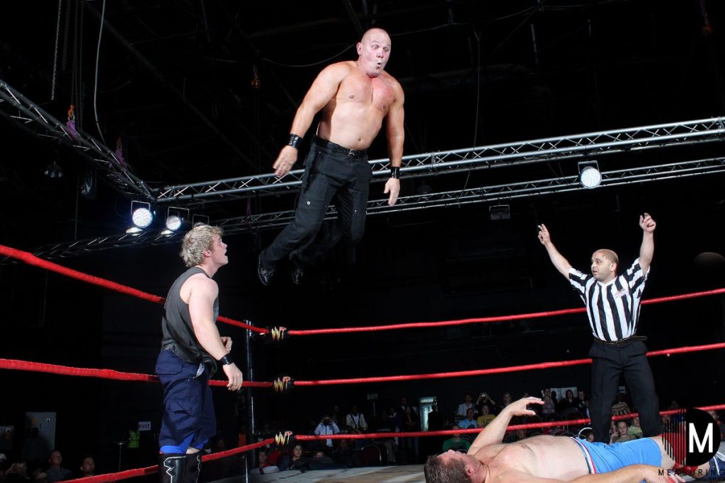 man jumping off top rope of wrestling ring