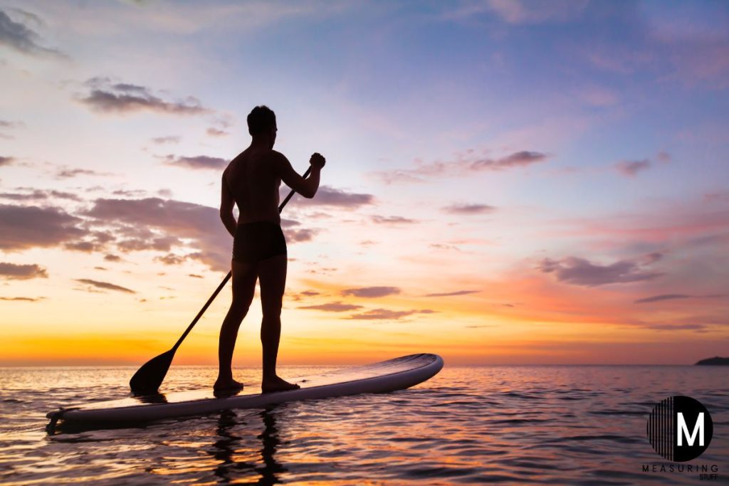 man on a paddle board at sunset