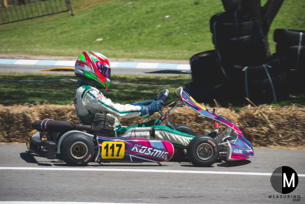 person wearing a helmet driving a multi colored go kart