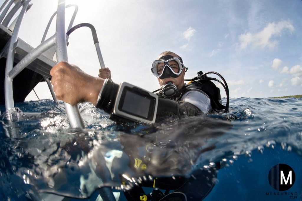 man hanging on a boat ladder going scuba diving