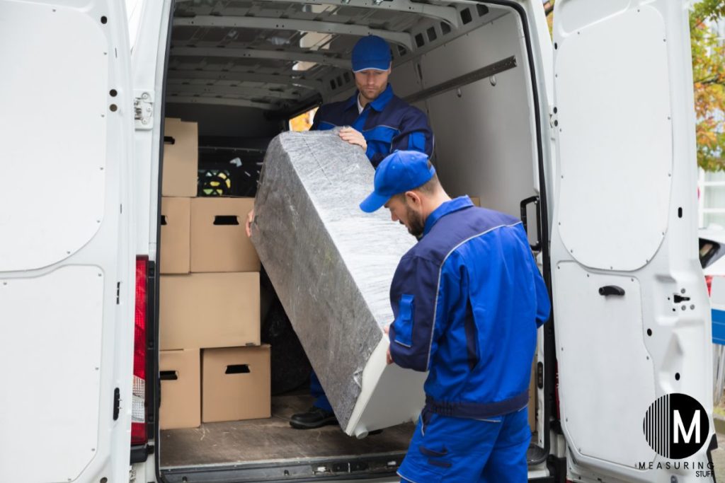 men unloading a large item from van 