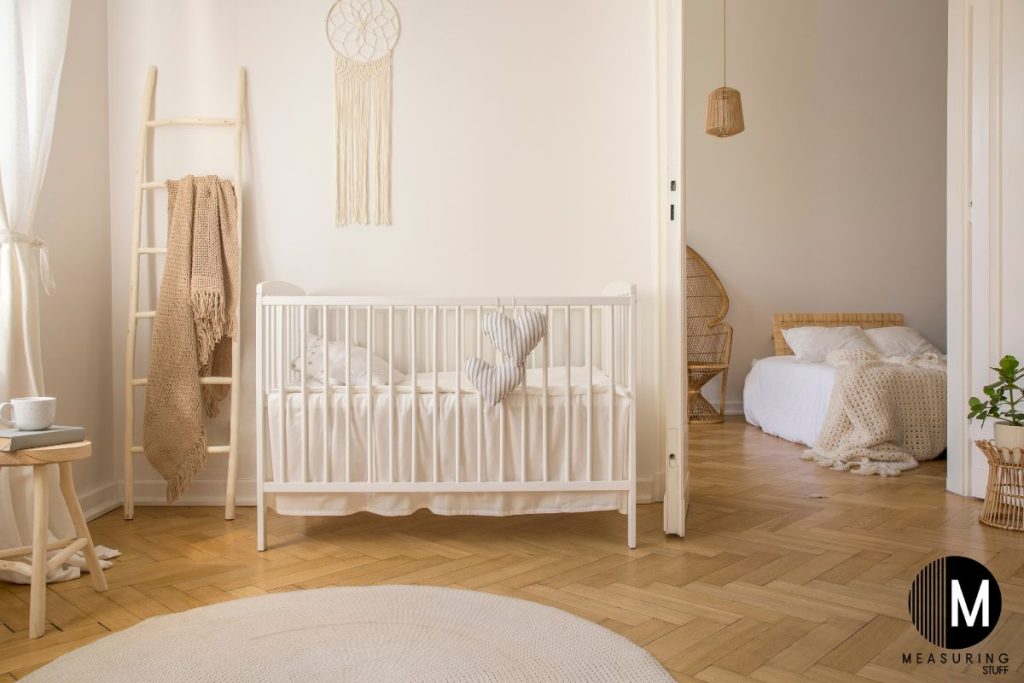 wooden baby crib against a wall with a ladder