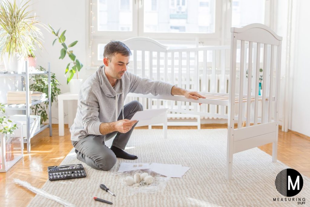 man putting together a wooden crib