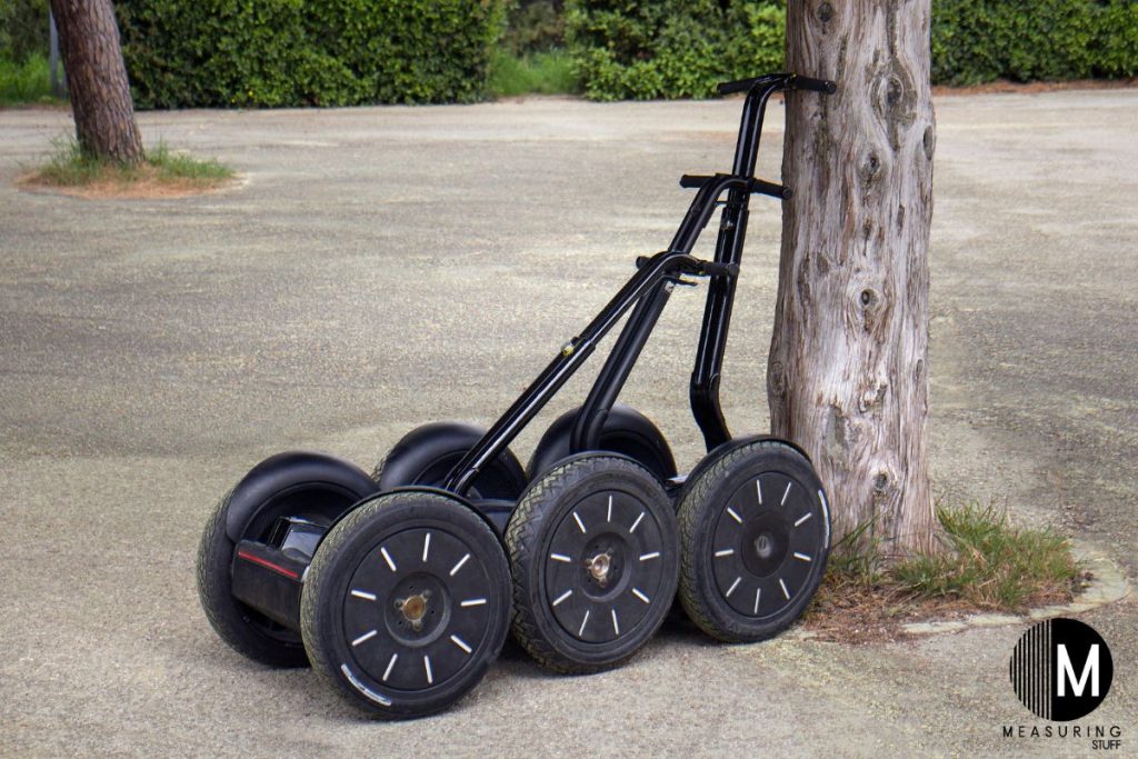 3 segways leaning against a tree