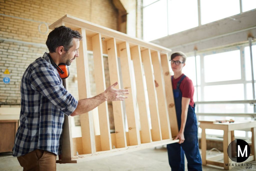 men carrying a wooden bed frame