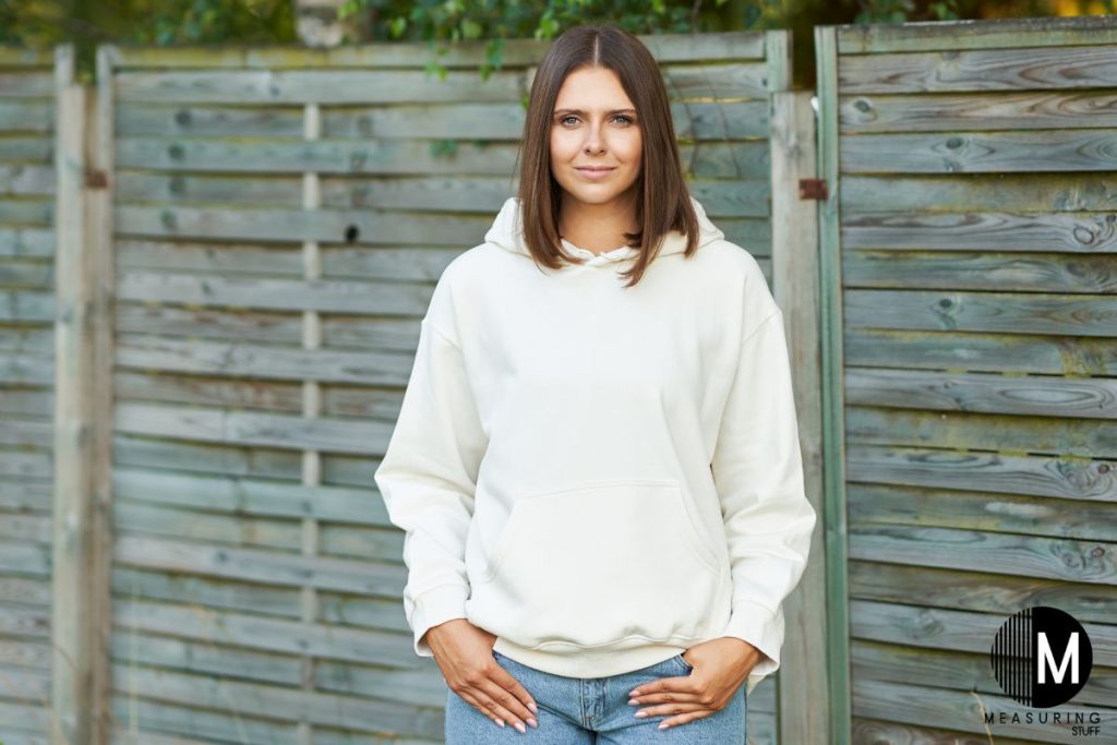 woman wearing a white hoodie next to a wood fence